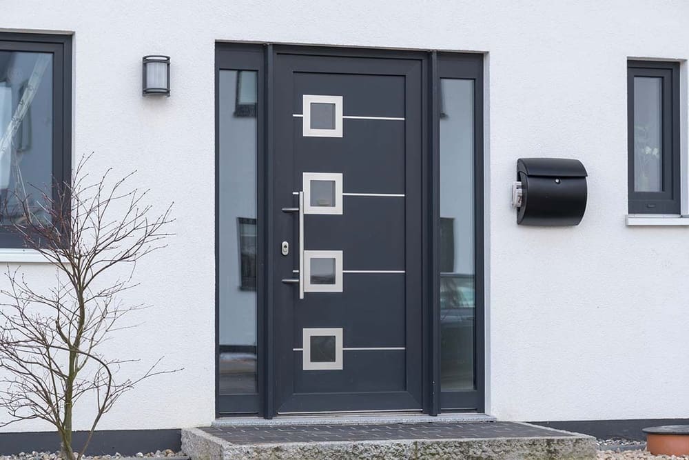 Anthrazitfarbene Haustür mit quadratischen Lichtausschnitten, Edelstahlgriff und zwei Glas-Seitenteilen